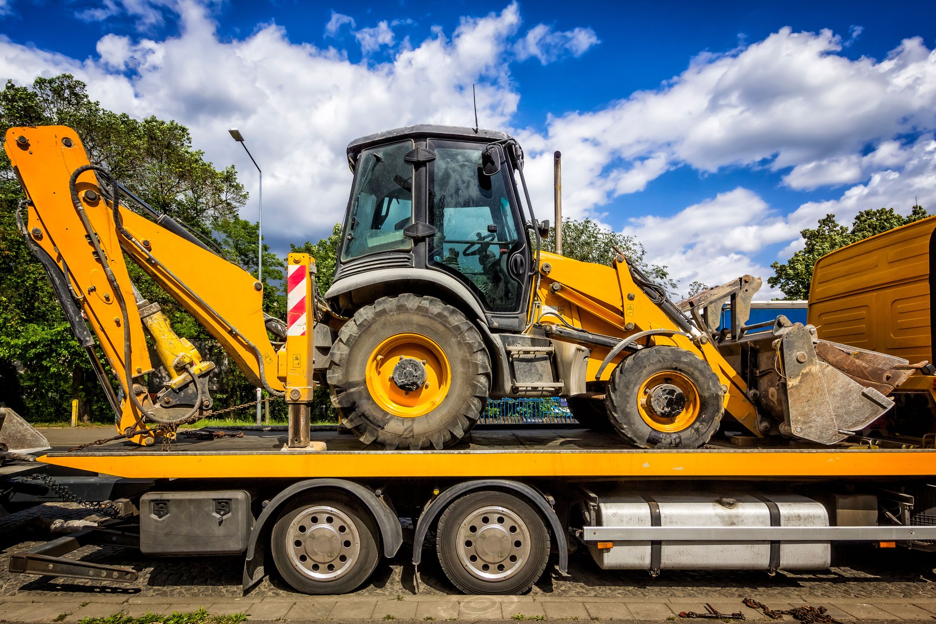 The trailer platform with yellow Backhoe